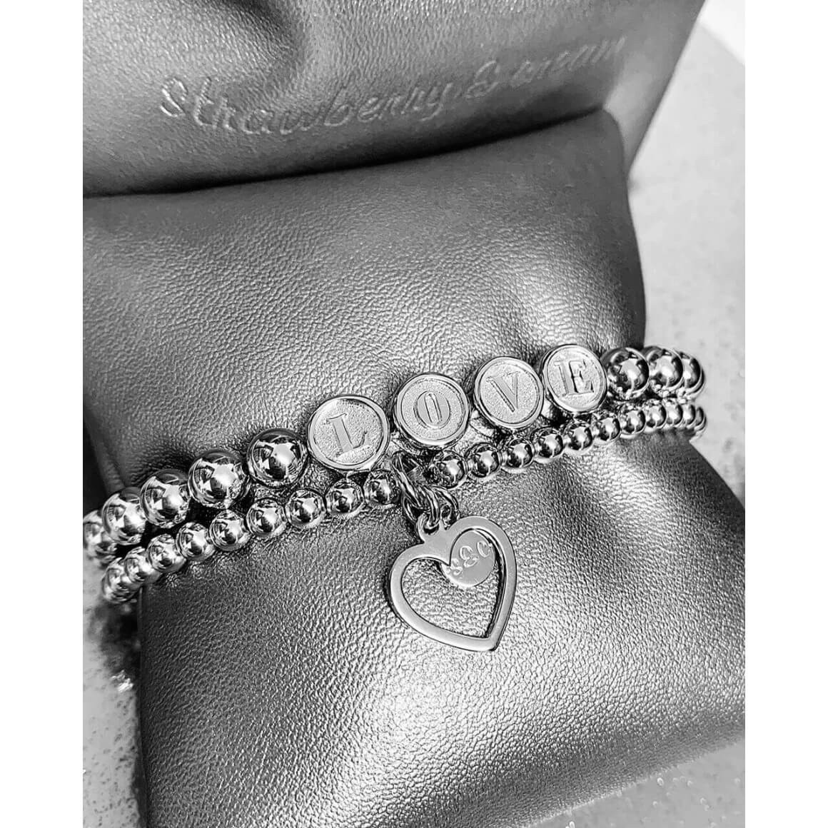 zwei Kugelarmbänder von strawberry & cream auf einem kleinen Schmuckkissen mit Love Schriftzug und Herzanhänger